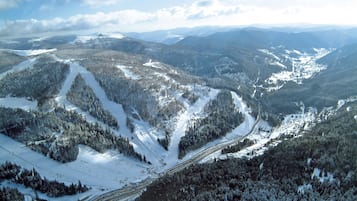 Paesaggio montano innevato con piste da sci e una seggiovia.