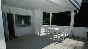 A covered porch with a table and chairs, a door, and a window.
