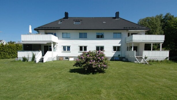 A two-story house with a large front lawn and a small garden.