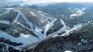 A snow-covered mountain landscape with ski trails and a ski lift.