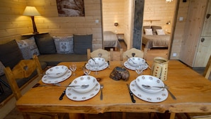 A wooden dining table set for four with plates, cutlery, and a candle holder.