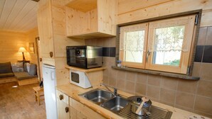 A compact kitchen with wooden cabinets, a microwave, a sink, and a window.