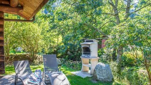 A patio with two lounge chairs, a stone barbecue grill, and a wooden pergola. - Magnifique Chalet rondins à La Bresse, tout confort, wifi, proche pistes, calme (La Bresse)