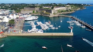 A harbor with boats docked, a lighthouse, and a fortified structure in the background. - Terraced house with 2 bedrooms in Le Palais center, pets allowed (Le Palais)