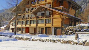 A multi-story wooden building with balconies, surrounded by snow and mountains. - Superbe appartement premium 42m² rénové terrasse wifi proche piste Hohneck (La Bresse)