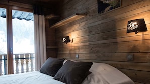 A bedroom with a bed, wooden walls, and two wall-mounted lights. - Superbe appartement premium 42m² rénové terrasse wifi proche piste Hohneck (La Bresse)