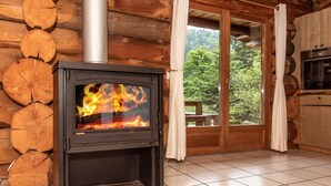 Un poêle à bois dans une cabane en rondins, avec vue sur la forêt.