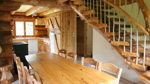 Un intérieur en bois comprenant une table et des chaises, un coin cuisine et un escalier en colimaçon.