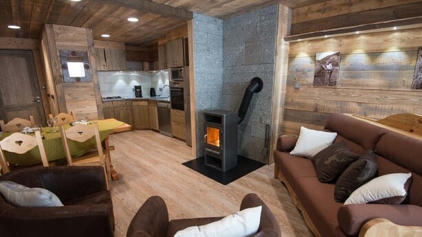 A cozy living area with a fireplace, wooden furniture, and a kitchen in the background. - Superbe appartement premium 42 m² La Bresse terrasse wifi vue montagne (La Bresse)