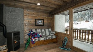 A cozy cabin interior with a wooden bench, a fireplace, a window with a view of a snowy landscape, and a balcony with a railing. - Superbe appartement premium 42 m² La Bresse terrasse wifi vue montagne (La Bresse)