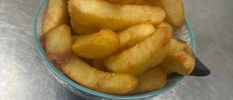 A bowl of golden-brown fries on a metallic surface.