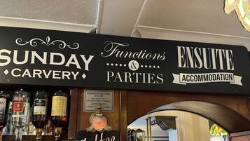 A bar area with a sign indicating services like Sunday Carvery, Functions & Parties, and Accommodation.