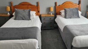 Two single beds with wooden headboards, grey bedding, and bedside tables with lamps. - The Kings Arms (North Walsham)