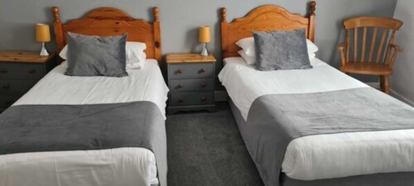 Two single beds with wooden headboards, grey bedding, and bedside tables with lamps. - The Kings Arms (North Walsham)