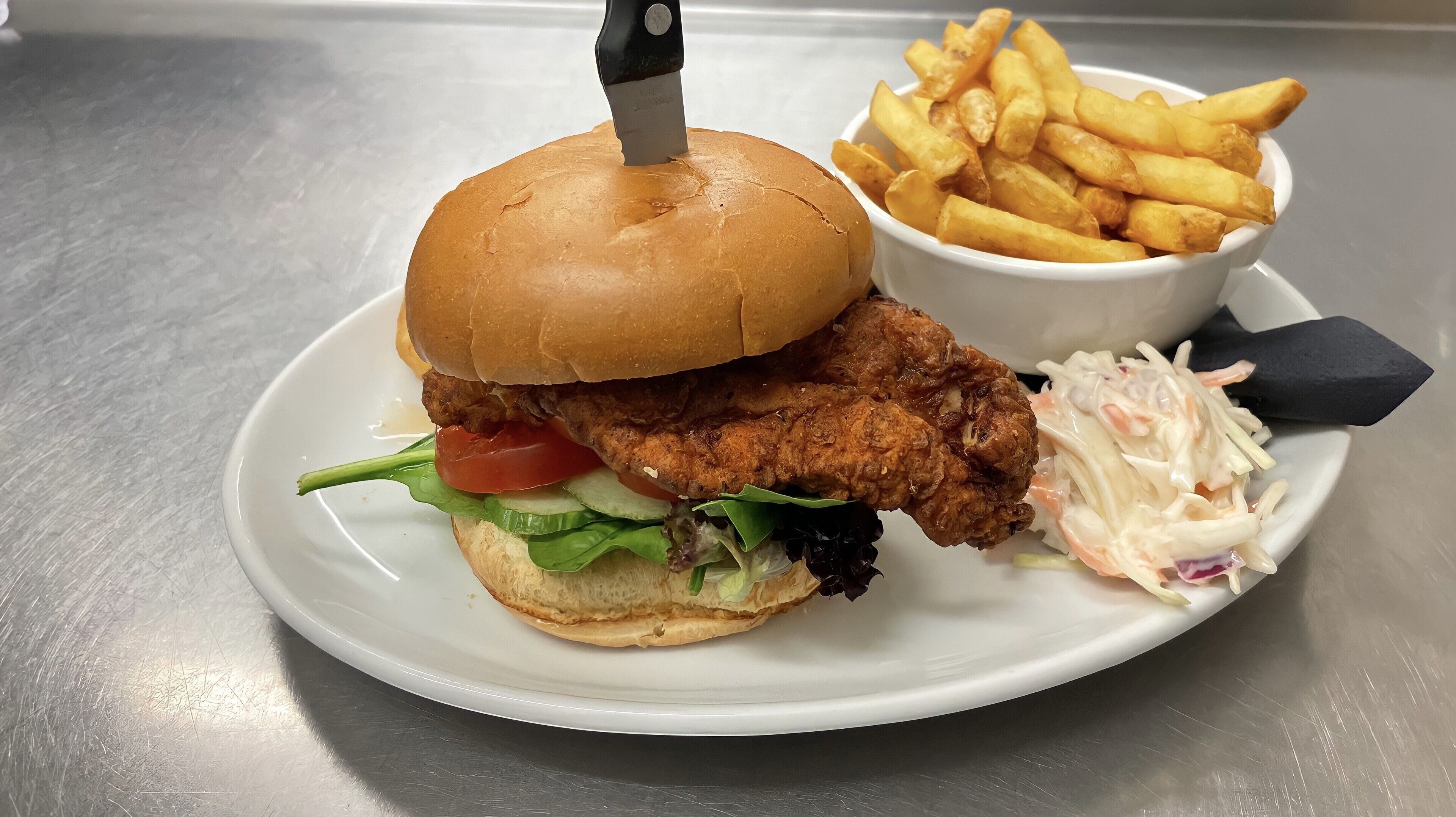 A plate with a fried chicken sandwich, fries, and coleslaw.