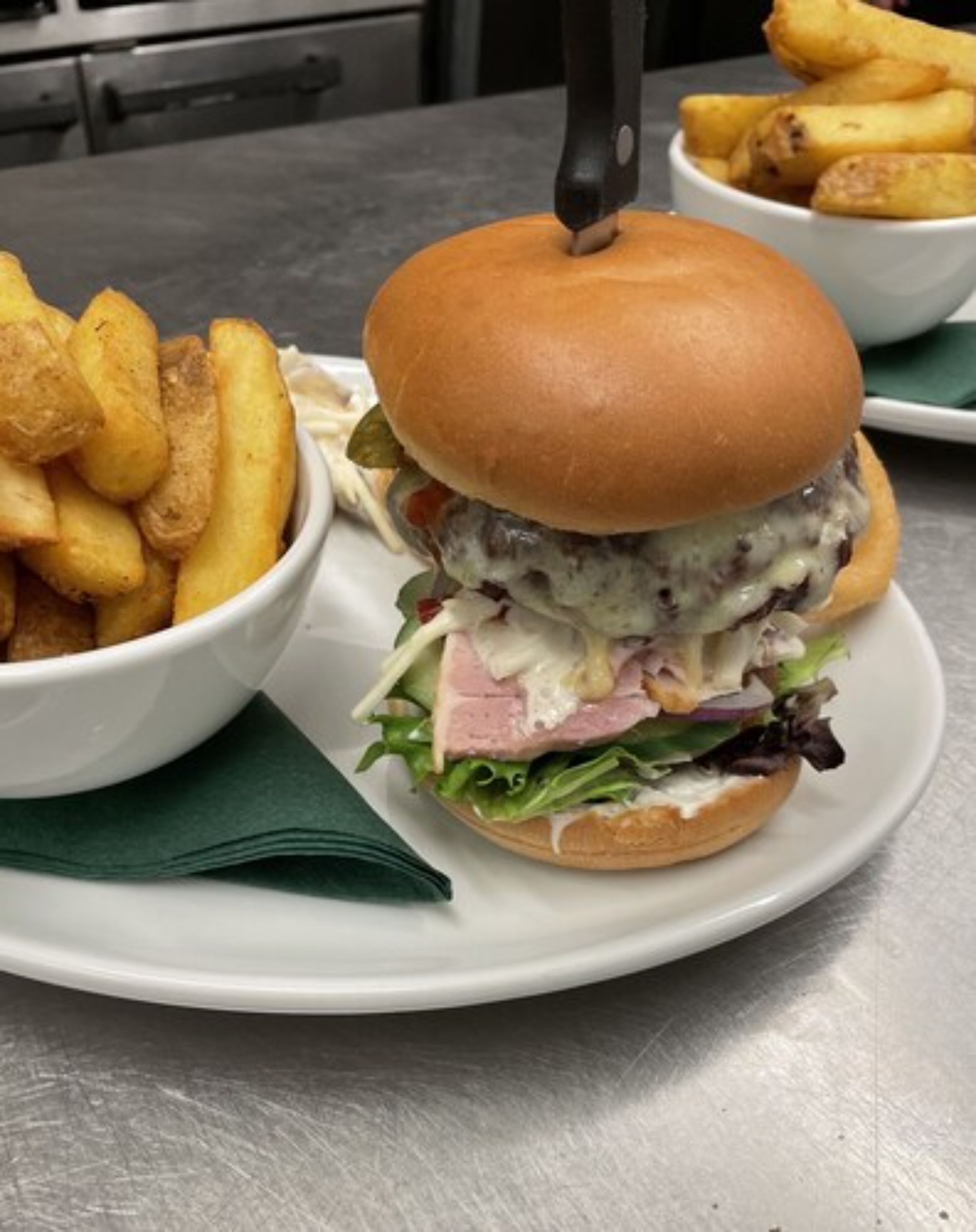 Ein Burger mit Brötchen, Salat, Käse und Soße, dazu Pommes.