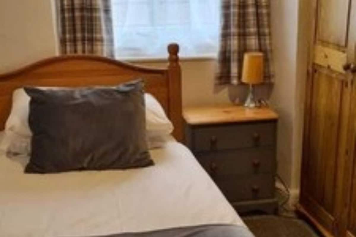 A bedroom with a bed, a nightstand, a lamp, and a wardrobe.