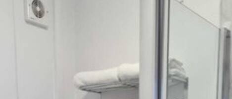 A compact bathroom with a toilet, a shower enclosure, and a sink.