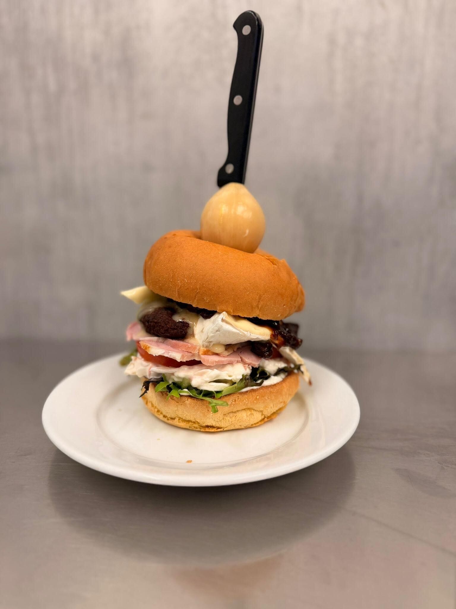 A sandwich on a white plate with a knife on top.