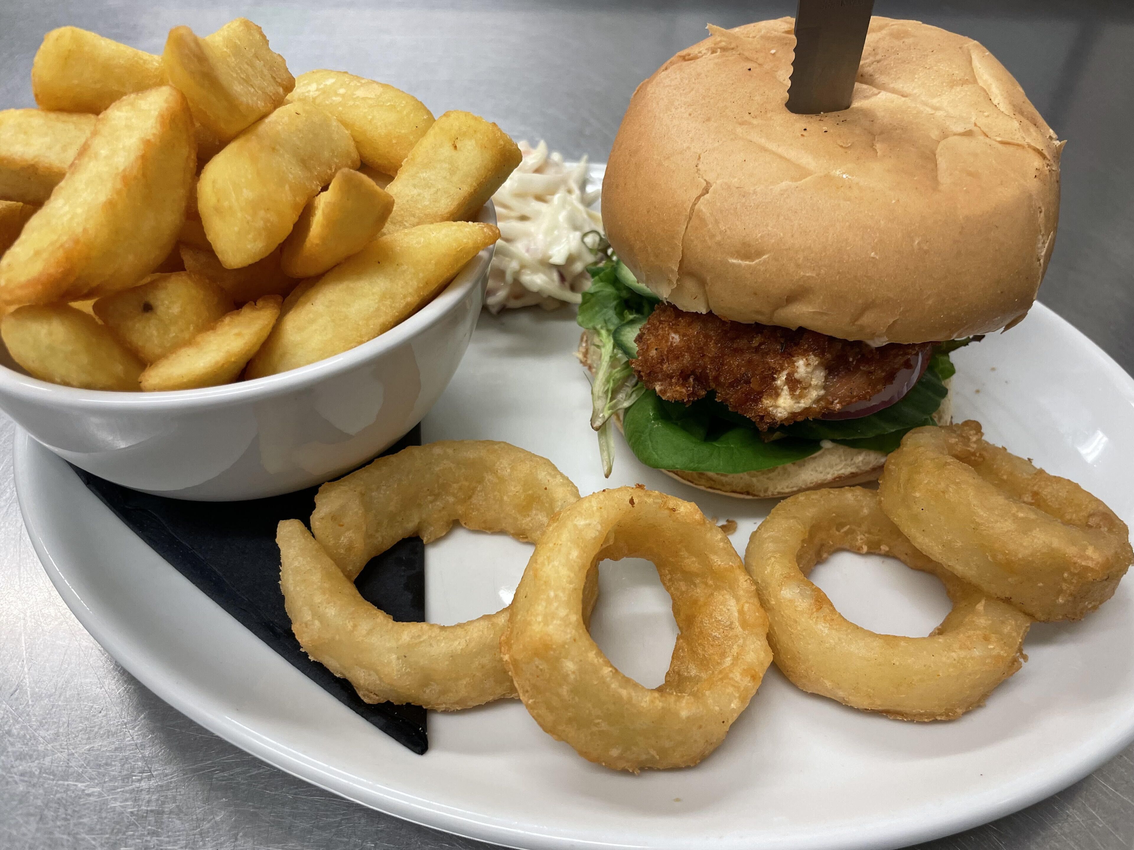A plate with a chicken sandwich, French fries, and onion rings.