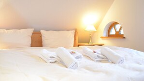 A neatly made bed with white linens and towels, a bedside lamp, and a window with a wooden frame. - FRITZ Aparthotel Potsdam (Potsdam)