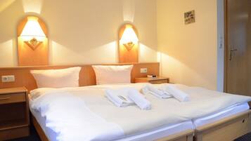 A hotel room with a double bed, two bedside tables, and two wall-mounted lamps.