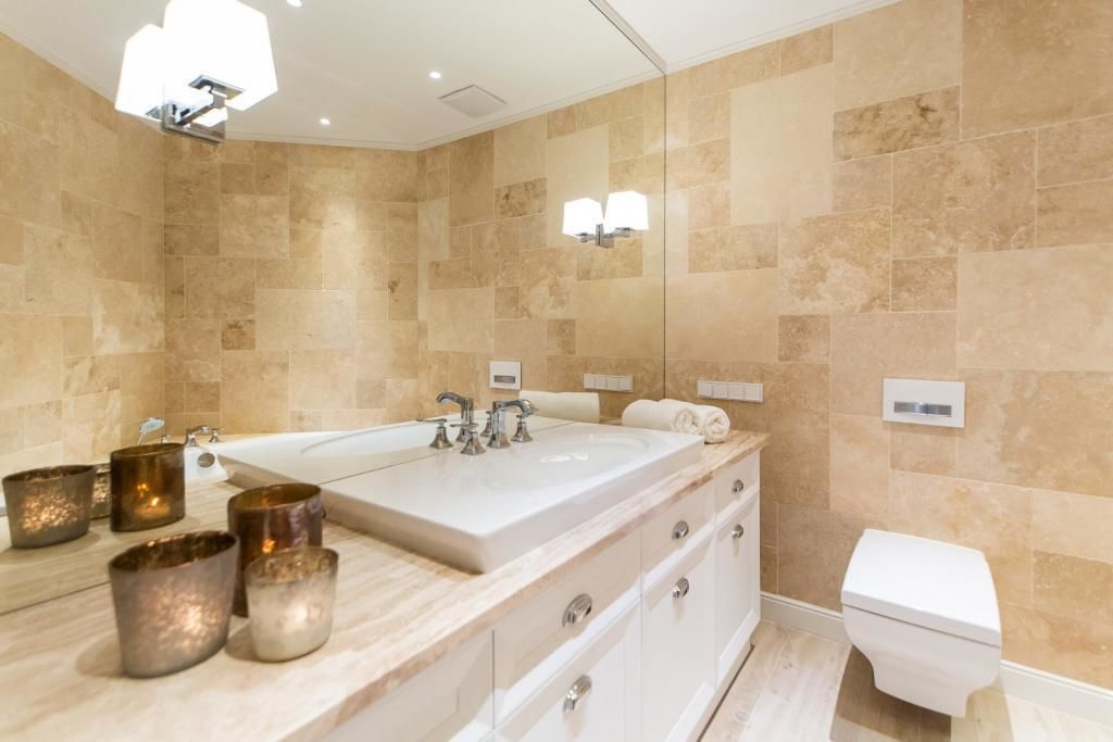 A modern bathroom with a large bathtub, a double sink, and a toilet.