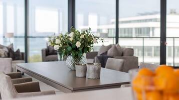 A modern living room with a large window, a dining table, and a view of the city skyline.