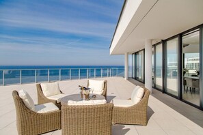 A balcony with wicker furniture and a view of the ocean.