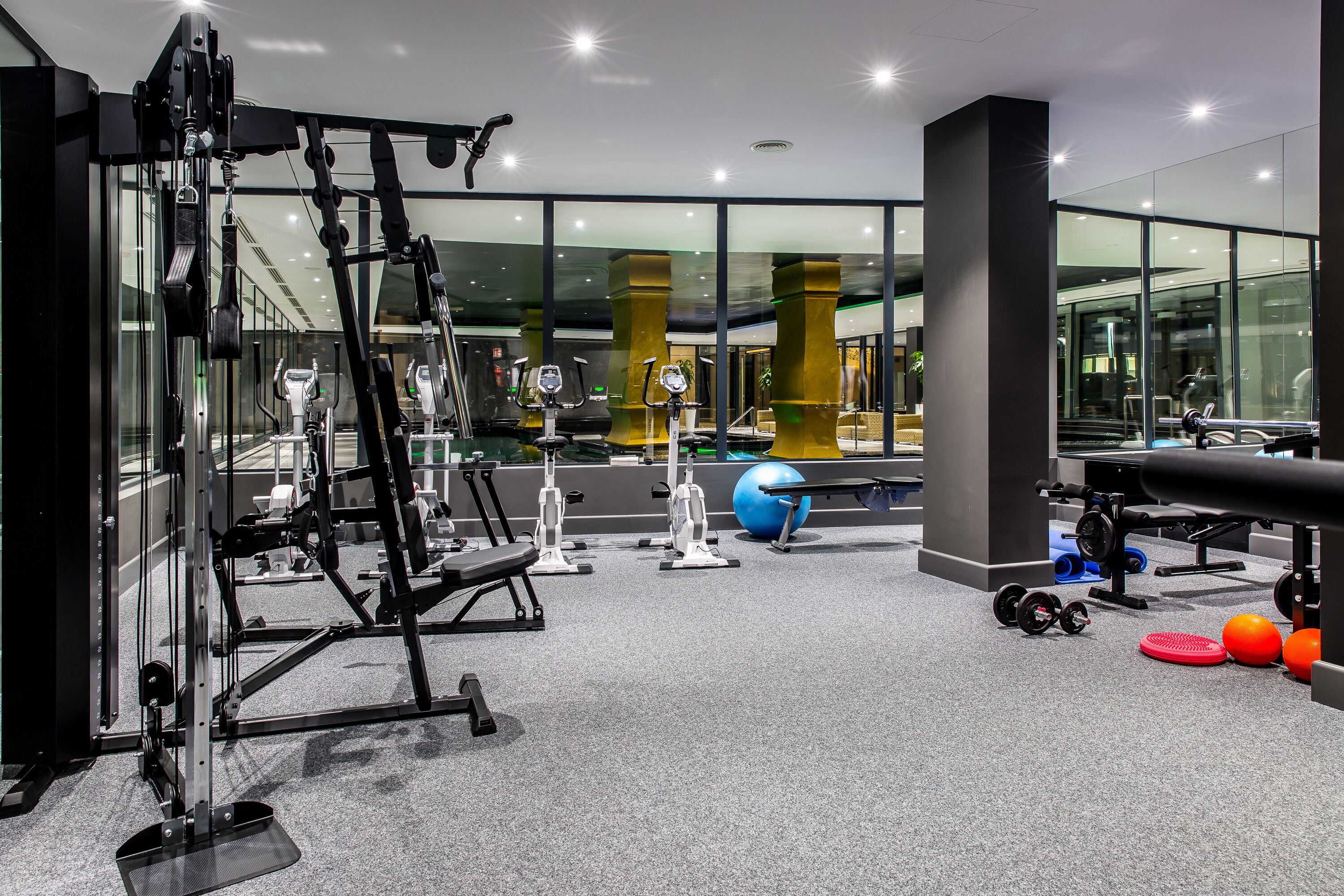 Een moderne sportschool met diverse fitnessapparaten, grote ramen en een ruime opzet.