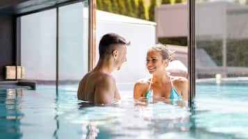 Una piscina techada, una piscina al aire libre, sombrillas