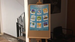 A bulletin board with health tips pinned on it, located in a hallway with a staircase and chairs. - Hostal Tropical (Oliva)