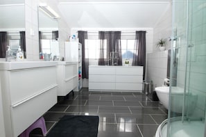 A modern bathroom with a white vanity, a bathtub, and a glass shower enclosure.