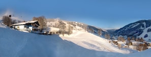 A snow-covered mountain village with a ski lift, houses, and a clear sky. - Saalbach Apartments Landhaus Bernkogel (Saalbach-Hinterglemm)