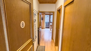 A hallway with wooden doors, a number 8 sign, and a view into a room with a table and chairs.
