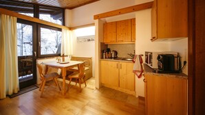 A wooden interior with a dining table, chairs, and a kitchen area with wooden cabinets and appliances.