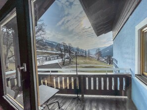 A balcony with a view of a snowy landscape and buildings. - Saalbach Apartments Landhaus Bernkogel (Saalbach-Hinterglemm)