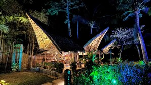 A traditional thatched-roof structure with a central open area, surrounded by lush greenery and palm trees. - Buko Beach Resort - Adults Only (El Nido)