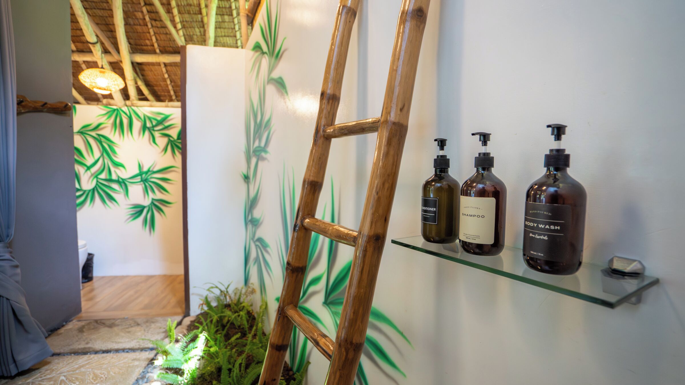 A bamboo ladder leaning against a wall with three bottles of shampoo and body wash on a shelf.