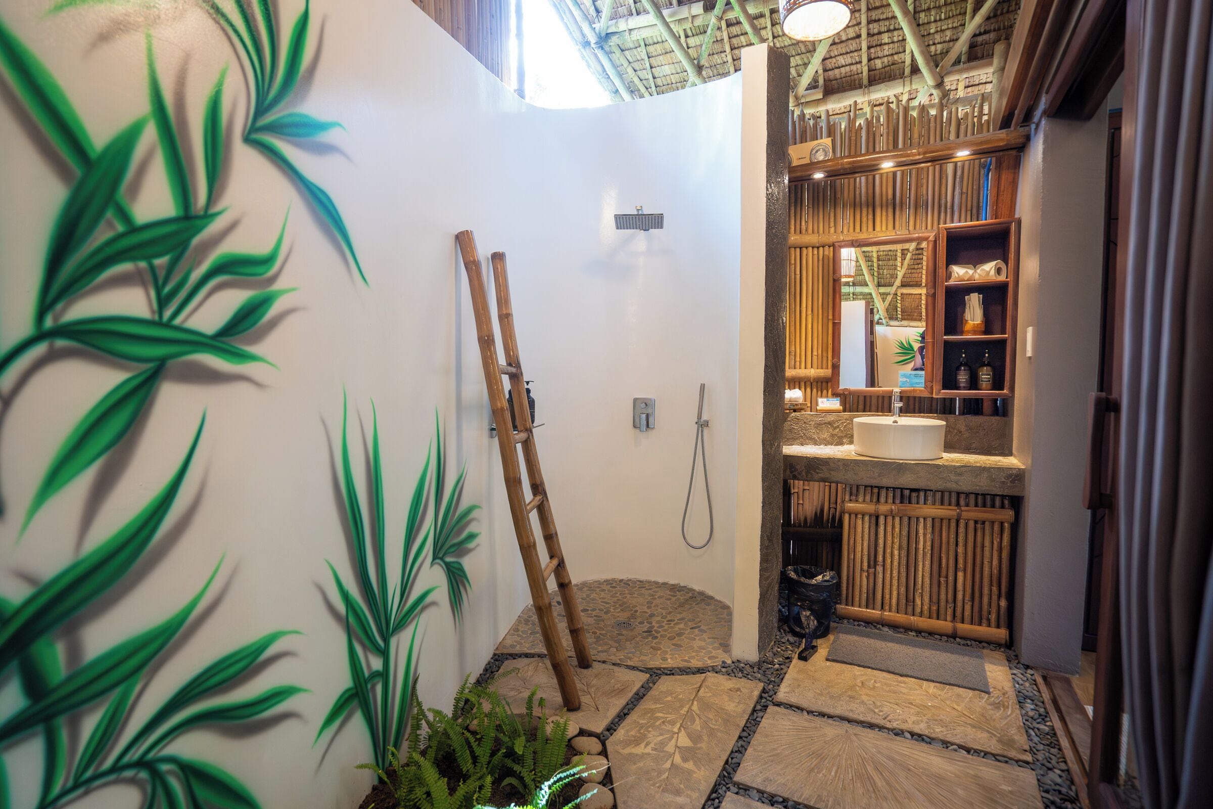 Un baño con una escalera de bambú, ducha y lavamanos con espejo.