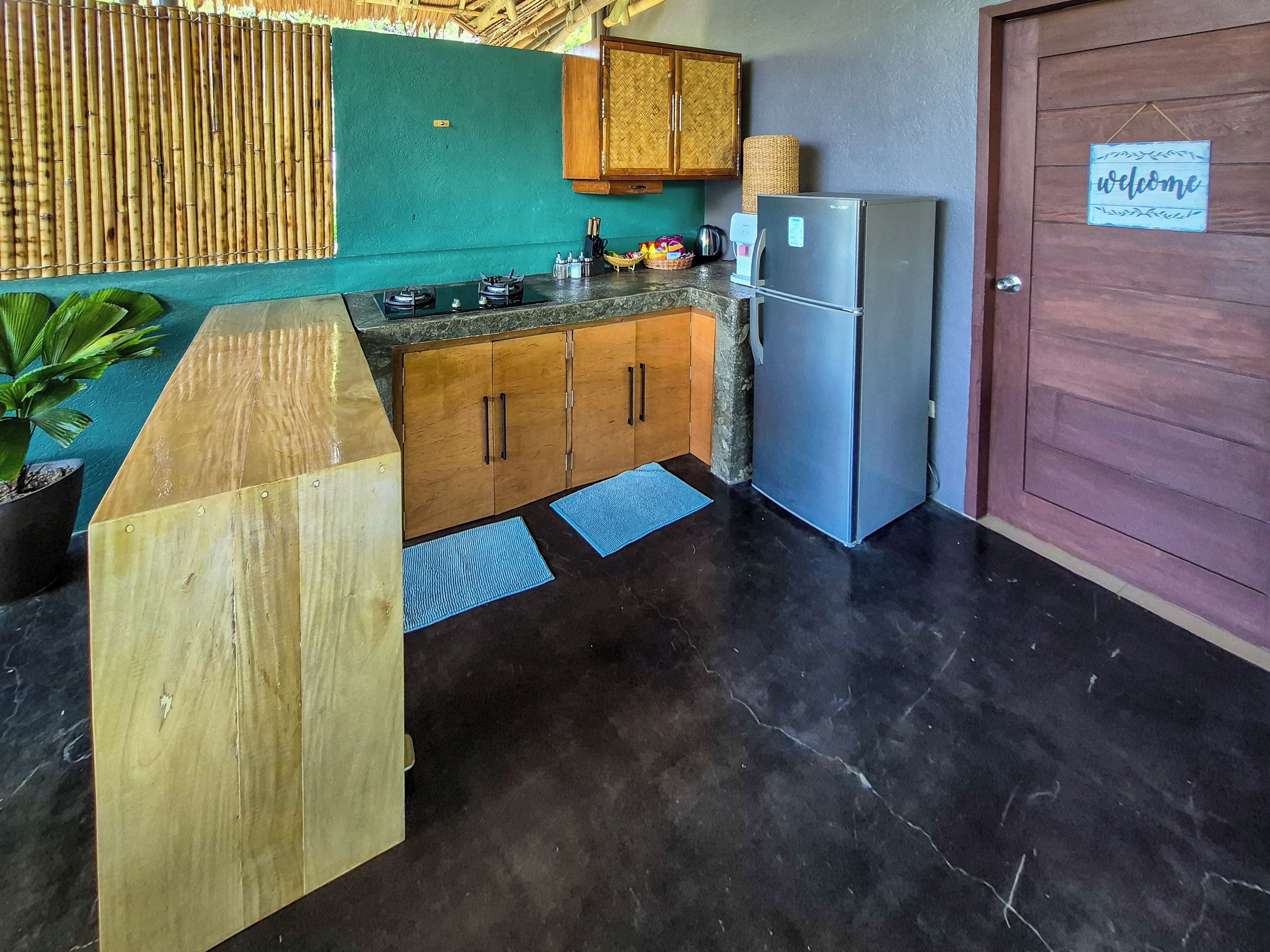A kitchen with wooden cabinets, a refrigerator, a stove, and a welcome sign on the door.