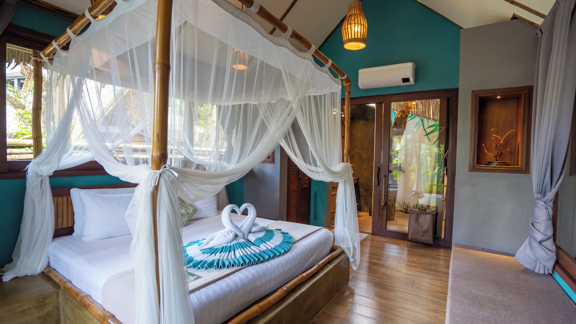 A four-poster canopy bed with white bedding and a heart-shaped pillow arrangement.