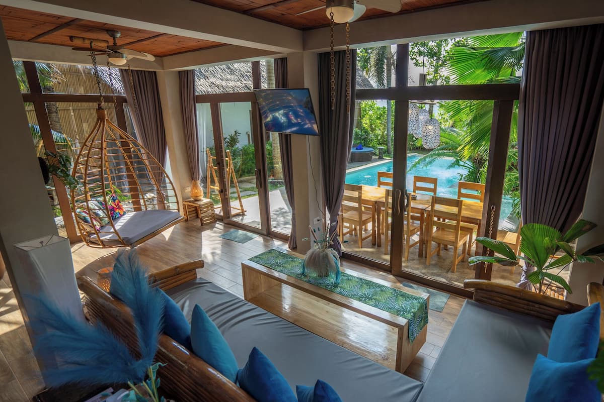 A spacious room with a pool view, wooden furniture, and large windows.