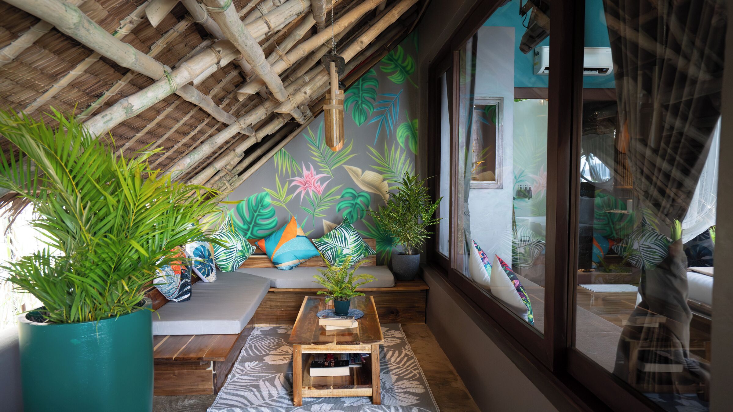 Una habitación acogedora con techo inclinado, un sofá, una mesa de centro y plantas grandes en macetas.