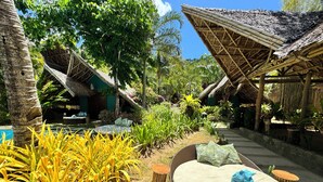 A tropical resort with thatched-roof huts, a pool, and lush greenery. - Buko Beach Resort - Adults Only (El Nido)