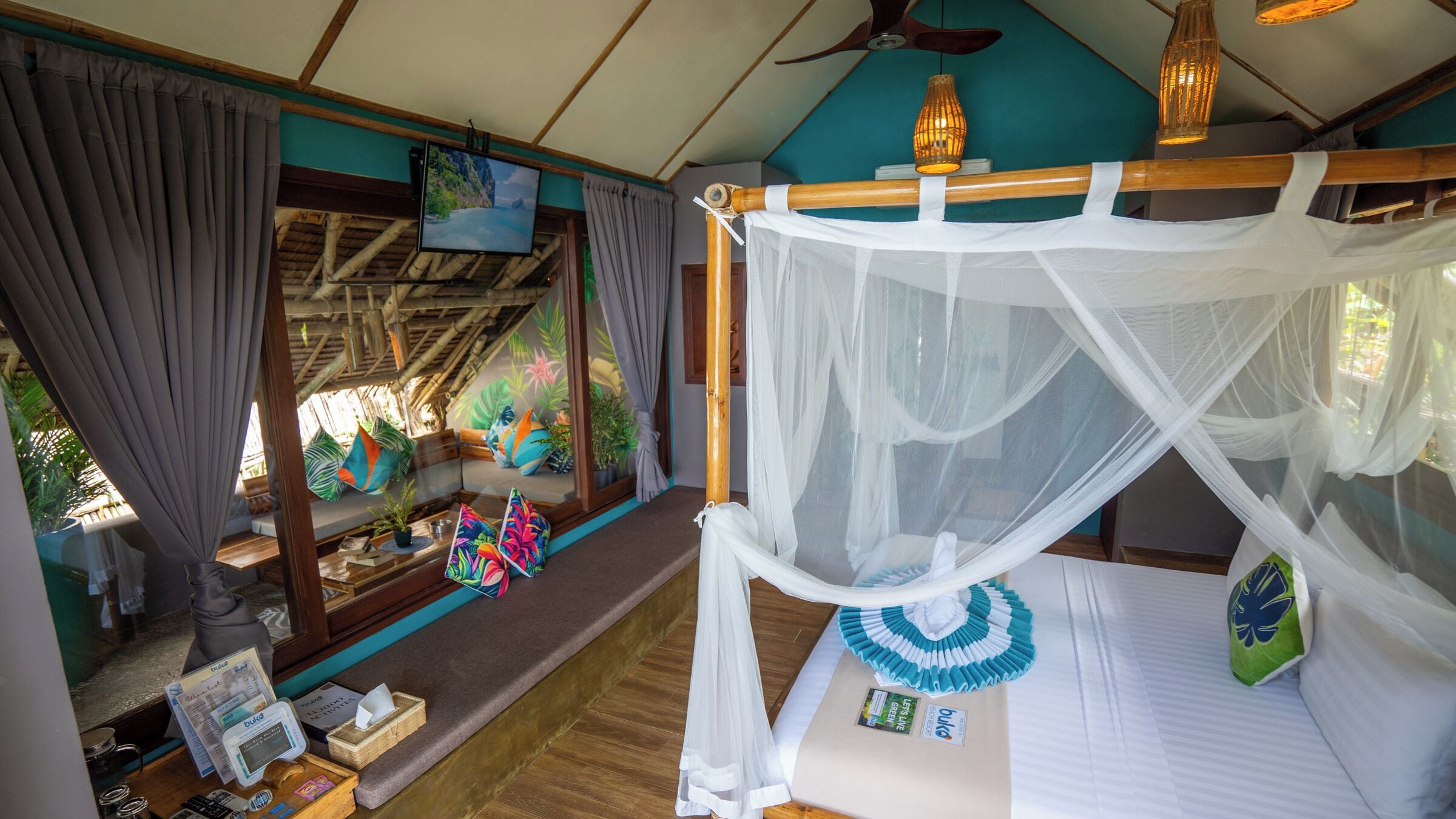 Ein Zimmer mit Bett, Fernseher, Deckenventilator und Blick ins Freie.