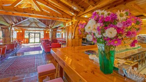 A wooden interior with a bar area, seating, and a large floral arrangement.