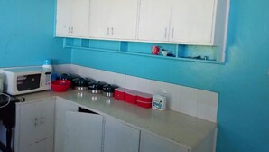 A kitchen with white cabinets, a microwave, and a countertop with various kitchen items.