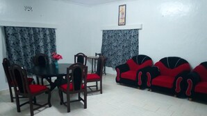 A dining area with a table and chairs, a sofa set, and a sewing machine.