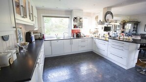 A modern kitchen with white cabinets, a black countertop, and a large window providing natural light. - Solferie Holiday Home Vardåsveien (Kristiansand)
